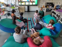 Eine Gruppe Kinder sitzt in Sitzsäcken vor einer digitalen Tafel