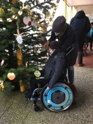 Kind im Rollstuhl schmückt den Weihnachtsbaum mit selbstgebastelten Ketten