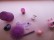 ein gemaltes lilafarbenes Chamäleon versteckt sich zwischen verschiedenen lilafarbenen Gegenständen