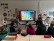 Schüler:innen sitzen vor einer digitalen Tafel, auf der ein Bilderbuchkino gezeigt wird