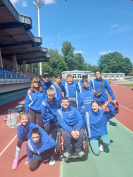 Schüler:innen in blauen Trainingsanzügen auf einer Tartanbahn