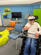 Ein Junge im Rollstuhl probiert eine VR-Brille aus