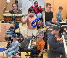 Schüler:innen spielen verschiedene Instrumente, Klavier, Schlagzeug, Schellenkranz, Trommel
